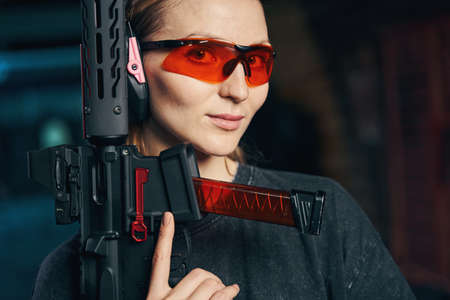 Beautiful lady in protective eyewear holding a weapon with one handの写真素材