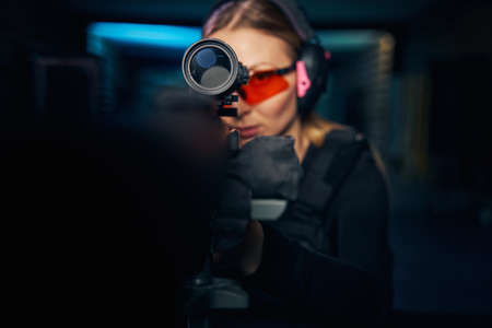 Focused young woman shooting a modern firearm