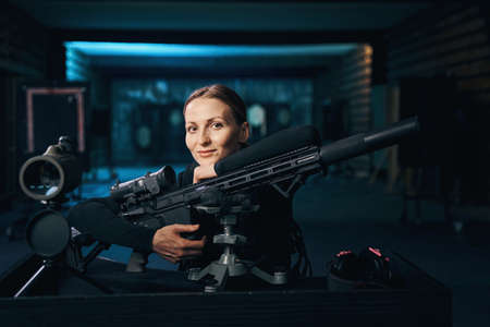 Pleased shooter sitting at the table with a machine gun