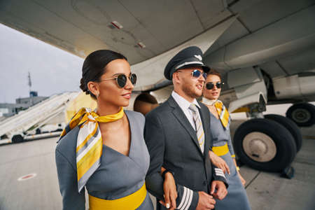 Pilot in a cap and stewardesses walking aheadの写真素材
