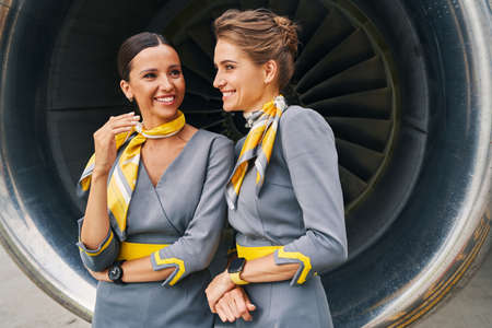 Joyous flight attendants standing by the turbofan engineの写真素材