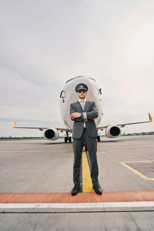 Tranquil aviator in uniform posing against a landed airlinerの写真素材