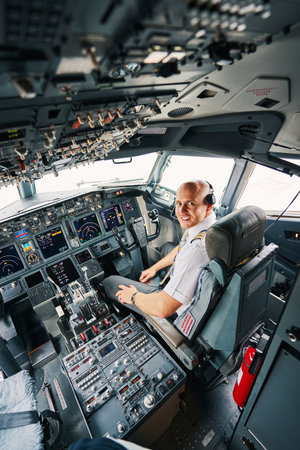 Pleased young pilot sitting in the cockpit before the take-off
