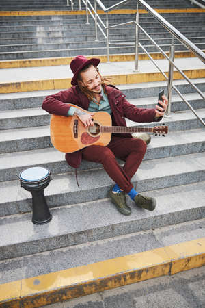 Positive delighted musician shooting video on his telephoneの写真素材