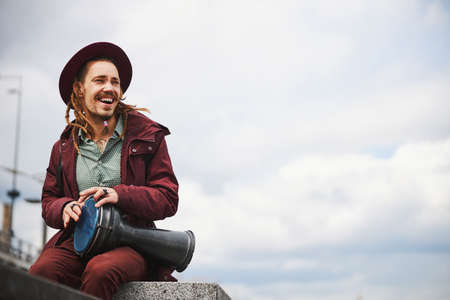 Happy male person creating melody on the embankment