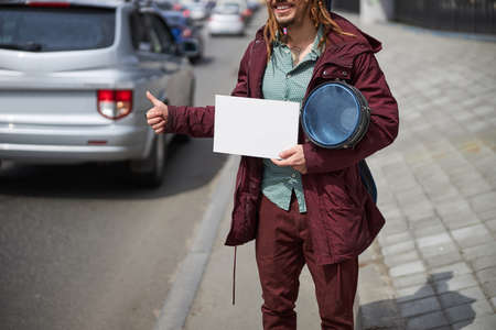 Positive delighted street musician waiting for car