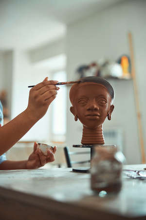 Female ceramist hand painting pottery in workshopの写真素材