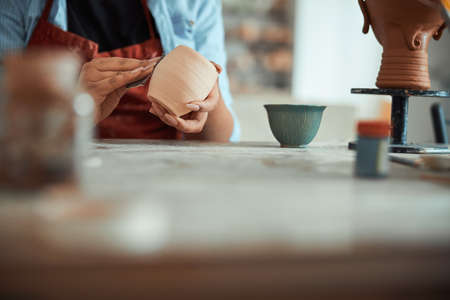 Female ceramic artist polishing clay pot in pottery workshop