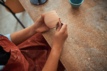 Craftswoman hands polishing clay pot in pottery workshop