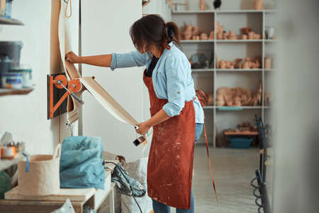 Female potter using burlap linen cloth in pottery workshop