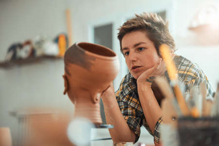 Nice female ceramist painting pottery in workshopの写真素材