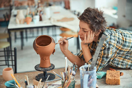 Nice female potter painting pottery in workshop