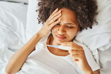 Sick young dark-haired woman lying in bed
