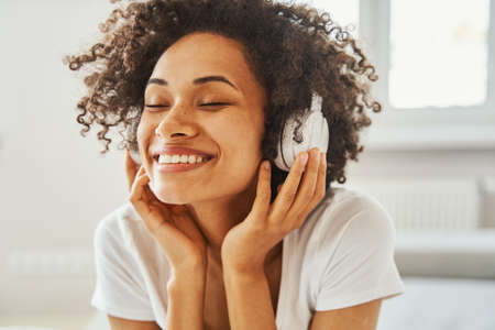 Joyful African American woman wearing wireless headphones