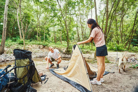 Happy young couple making camp in forestの写真素材
