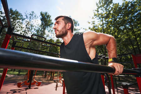 Motivated young man training on parallel bars