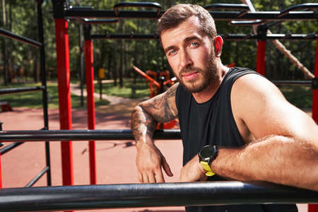 Relaxed young muscular man training on sportsground