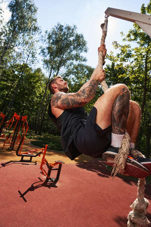 Young male doing strength workout on sportsground