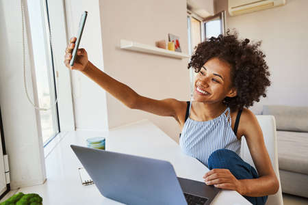 Smiling lady taking a selfie by the window