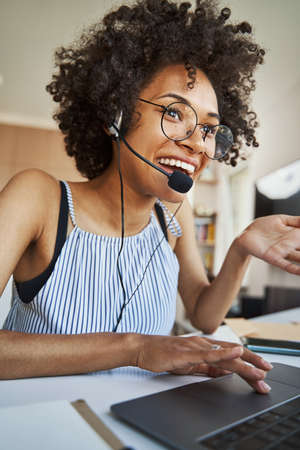Joyful female freelancer in the headset communicating online