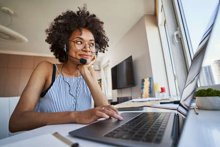 Contented telecommuter in headphones with a microphone looking away