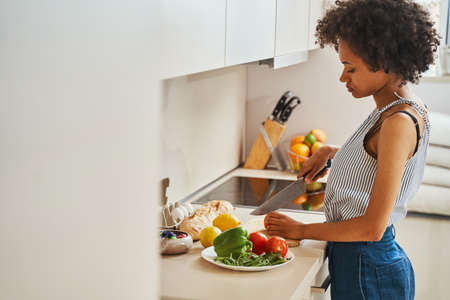 Serious focused lady preparing a vegetable salad
