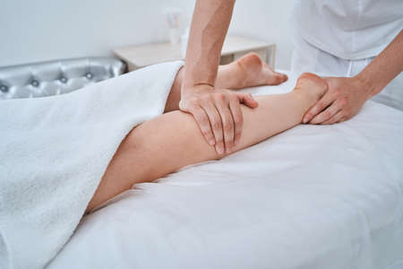 Massotherapist giving his patient a leg massageの写真素材