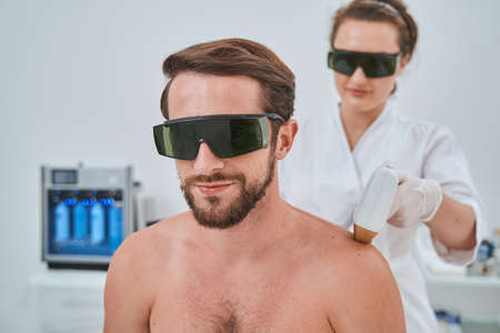 Male patient in protective eyeglasses during a cosmetic procedureの写真素材