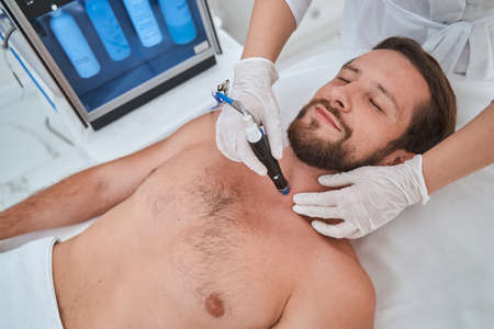 Male patient getting a skin treatment in a beauty salonの写真素材