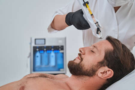 Patient getting a subcutaneous injection into his forehead with a mesogunの写真素材