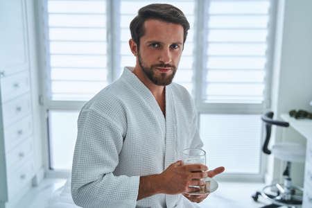 Patient in a waffle weave bathrobe holding a non-alcoholic beverageの写真素材