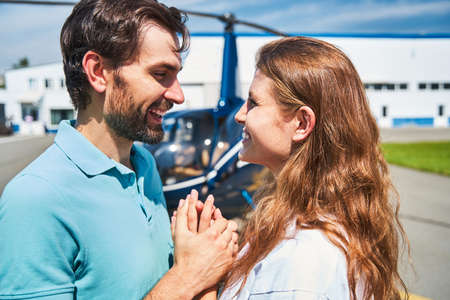 Happy romantic tourist couple standing by helicopterの写真素材