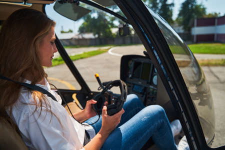 Female helicopter pilot examining headset before flightの写真素材