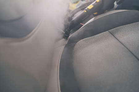 Steam cleaning close-up in auto detailing. Car seats wash with steamerの写真素材