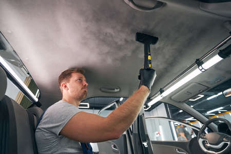 Service worker using vapor cleaner automobile cabin. Steam sterilizingの写真素材