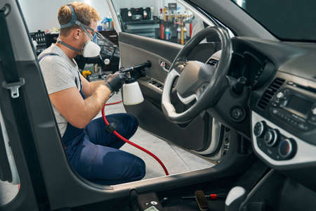 Worker conducts chemical cleaning of steering wheel. Disinfectionの写真素材