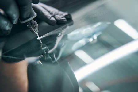 Service worker check crack on car window closeup. Windshield repairの写真素材