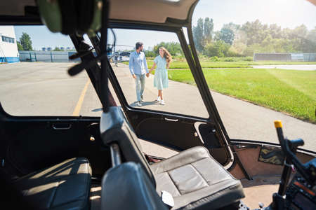 Smiling woman and man walking towards helicopterの写真素材