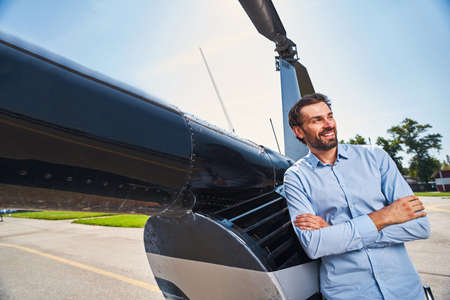 Joyous guy standing by helicopter at heliportの写真素材