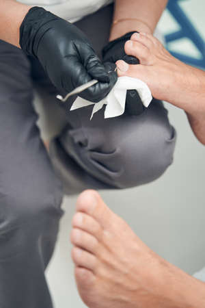 Female specialist hands doing pedicure for man in salonの写真素材