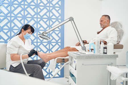 Man having hardware pedicure procedure in cosmetology salonの写真素材