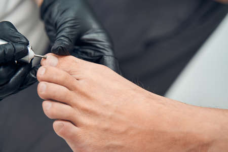 Beautician hands doing hardware pedicure for male clientの写真素材