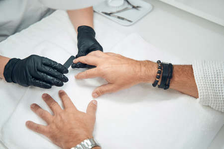 Professional manicurist filing man nails with emery boardの写真素材