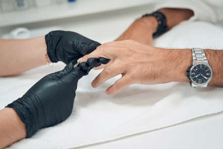 Manicurist cutting cuticle on man finger with manicure nippersの写真素材