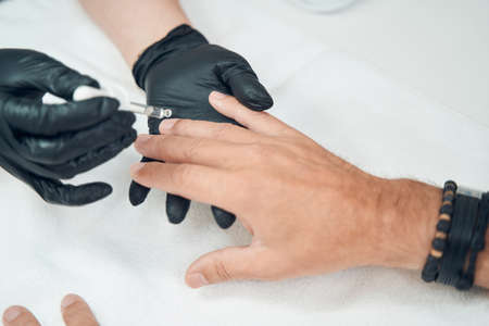 Manicurist applying serum on man nails after manicureの写真素材