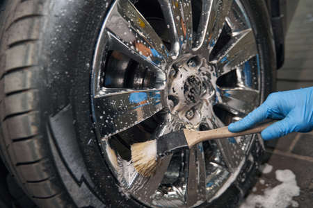Car detailing studio worker cleaning car wheel with brushの写真素材