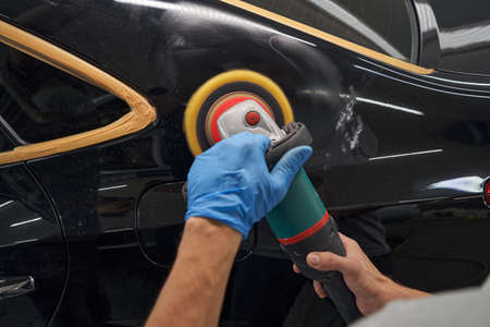 View of person hands polishing car with orbital polisher