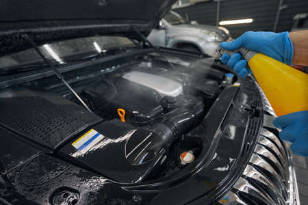 Professional car washer cleaning car by washing fluid in service station