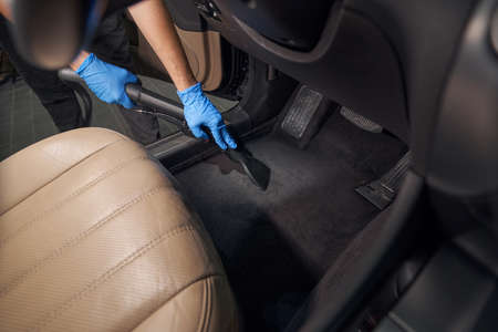 Worker cleans car interior with vacuum cleanerの写真素材