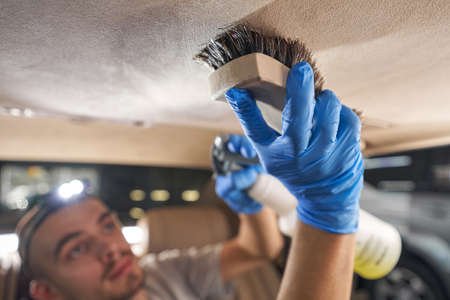 Service worker with brush wipes car trim at renewing service stationの写真素材